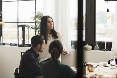 Business people listening to coworker during meeting in office