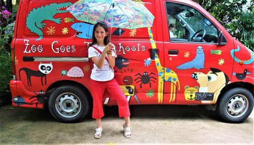 Full length portrait of young woman standing in car