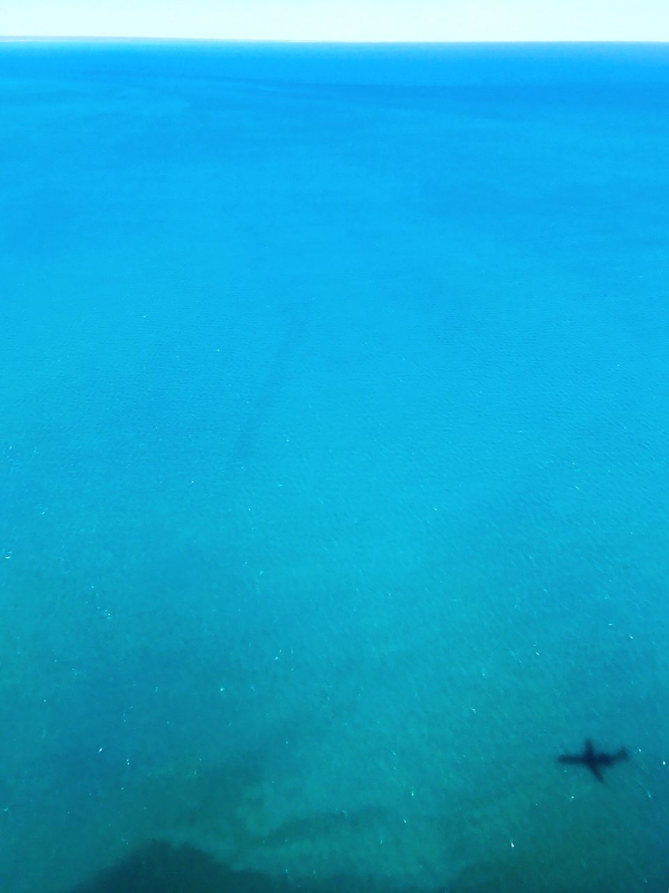 CLOSE-UP OF BLUE SEA AND AIRPLANE AGAINST SKY