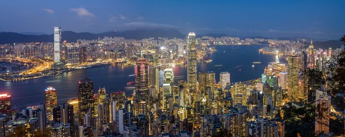 Illuminated modern buildings in city against sky at night