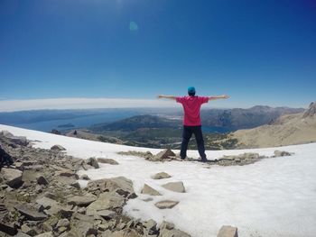 Rear view of man standing on mountain during winter