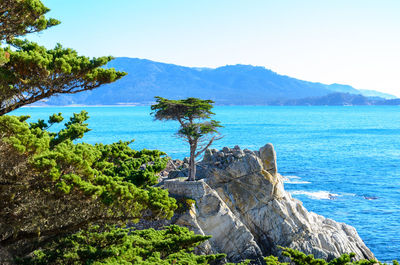 Scenic view of sea and mountains against clear blue sky