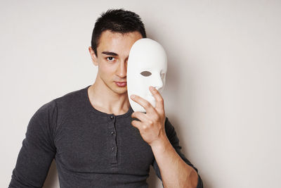 Cropped hand of woman wearing mask against white background