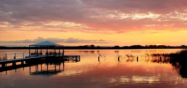 Silhouette pier over lake against sky during sunset