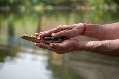 Image of the hands of a young man- praying in the morning holding kosha kushi. 