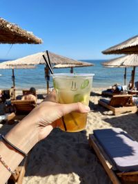 Midsection of woman holding drink at beach