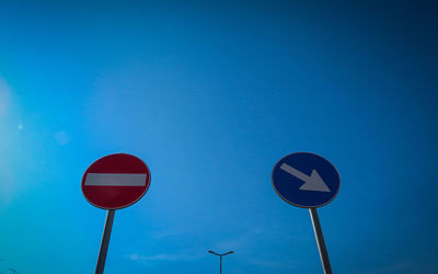 Low angle view of road sign against blue sky