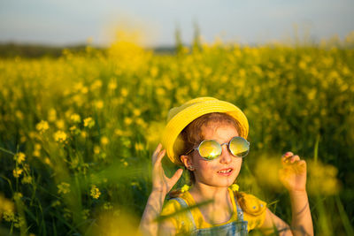 Portrait of cute girl with yellow flowers on field