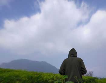 Rear view of man on field against sky