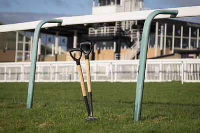 Shovels by railing at racecourse