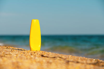 Close-up of yellow flower on beach against clear sky