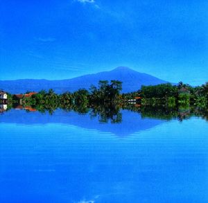 Scenic view of lake by trees against blue sky