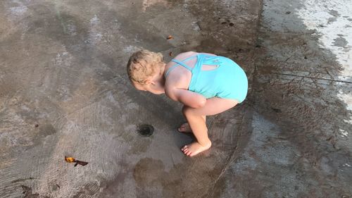 High angle view of girl looking into manhole