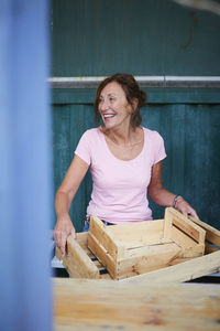 Happy senior gardener with crates sitting at yard