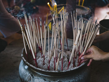 Cropped image of person holding burning incense sticks in temple