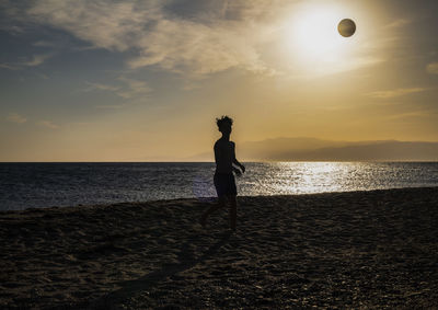 Man standing on beach against sky during sunset