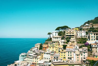 Buildings by sea against blue sky