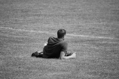 Rear view of man sitting on field