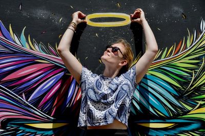 Woman standing against graffiti on wall