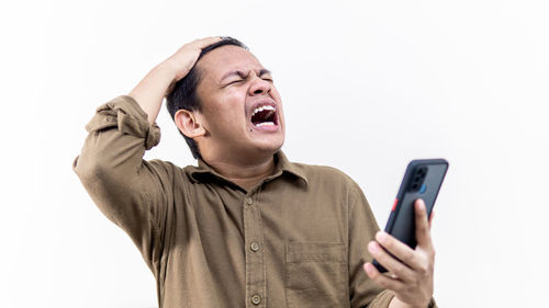 Mid adult man using smart phone against white background