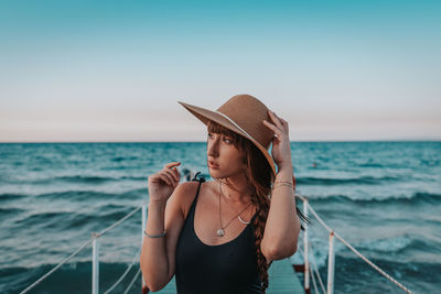Woman wearing hat standing against sea