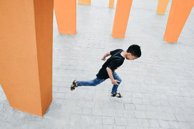 High angle view of playful boy running on footpath in city