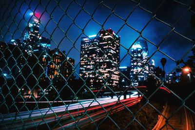 View of cityscape seen through chainlink fence