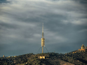 Communications tower in city against sky