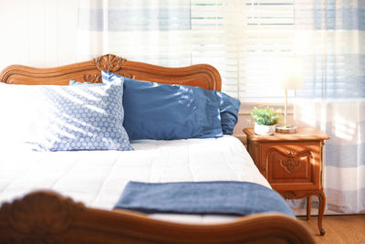 Plant and lamp on table by bed in bedroom at home