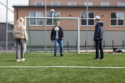 Friends playing soccer on school soccer field