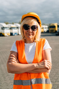 Portrait of young woman wearing sunglasses while sitting on street