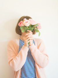 Midsection of woman holding bouquet against white background