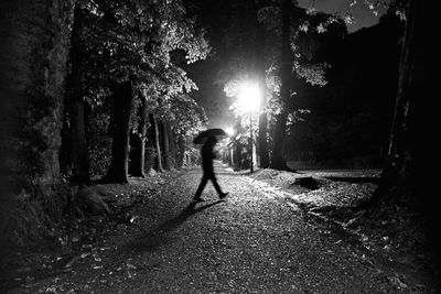 Side view of woman walking on street amidst trees in forest