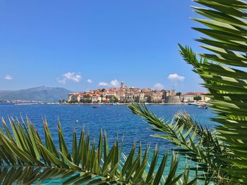 Scenic view of sea by buildings against blue sky