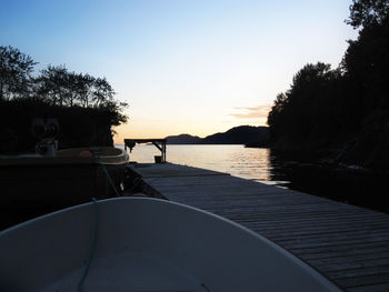 Silhouette trees by sea against clear sky during sunset