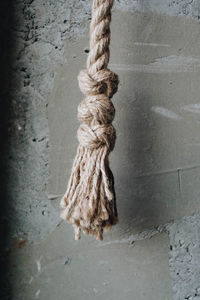 Close-up of rope tied on wooden post against wall