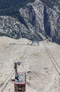 High angle view of overhead cable car hanging on cable over mountain during sunny day