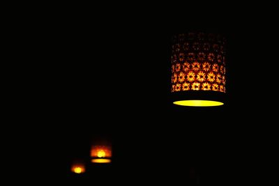 Low angle view of illuminated lighting equipment against black background