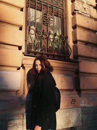 Young woman standing against brick wall