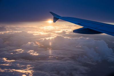 Airplane wing against sky during sunset