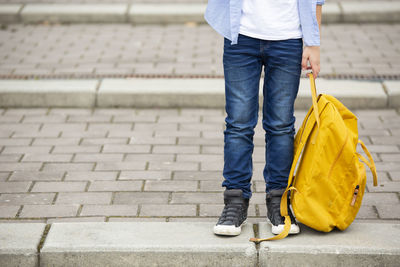 Low section of boy holding backpack