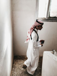 Side view of man standing against white wall