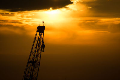 Low angle view of crane with hook at dusk