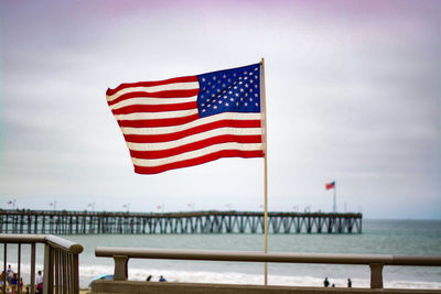 American flag flying on beach against sky