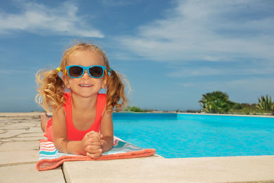 Portrait of young woman wearing sunglasses against swimming pool