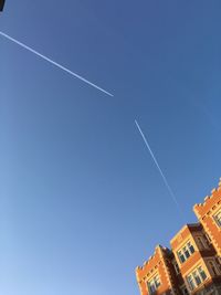 Low angle view of vapor trails in clear blue sky