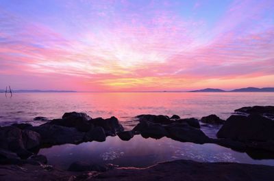 Scenic view of sea against dramatic sky during sunset