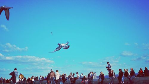 People flying against blue sky