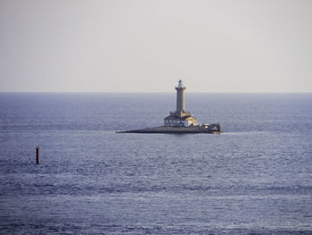 Lighthouse by sea against clear sky