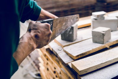 Cropped hands of man cutting concrete on table